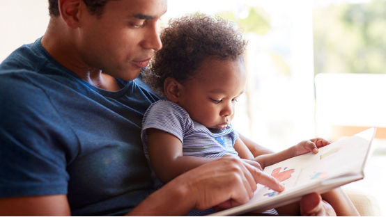 Father and child read a book together, with donut pillows to enhance reading comfort in the home corner