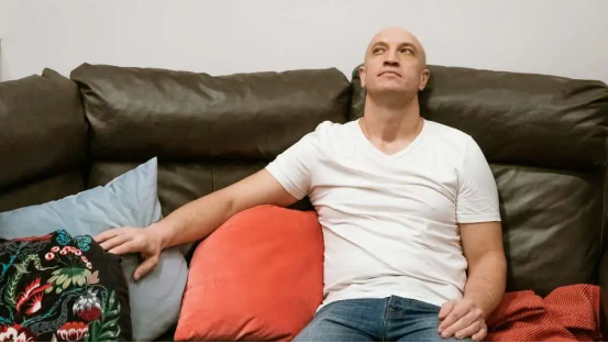 Person relaxing on a sofa (experiencing cool, all-day summer comfort, made possible by the bamboo charcoal donut pillow)