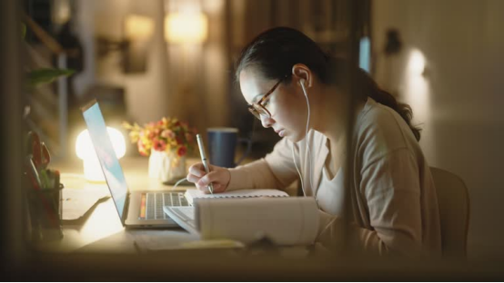 A student studying late, using a donut pillow on their desk chair to stay comfortable during long sessions.