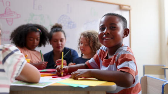 Kids creating art in class, staying comfortable and focused with a donut pillow for support.