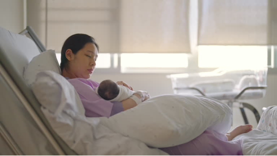 This postpartum mom uses a donut pillow to ease tailbone pain while resting with her baby.