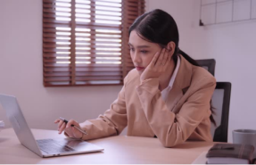 A fatigued office worker at her desk, showing how a memory foam donut pillow eases burnout-related discomfort.
