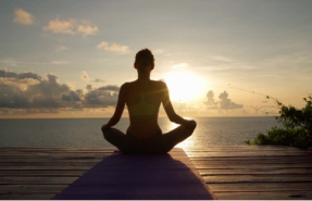 A person meditating at sunset, with a donut pillow enhancing seated comfort for longer practice.
