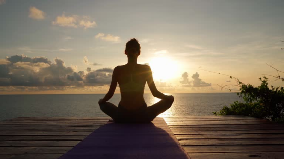 A person meditating at sunset, with a donut pillow enhancing seated comfort for longer practice.