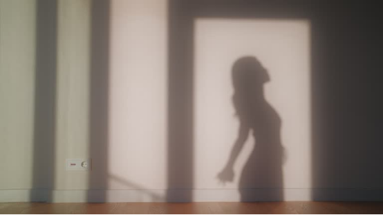 A woman's silhouette is cast on a wall, suggesting post-workout relaxation where a donut pillow can aid muscle relief.