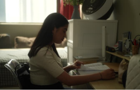 A student studying at a desk, showing how a space-saving donut pillow adds comfort to compact dorm spaces.