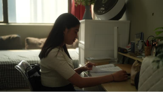 A student studying at a desk, showing how a space-saving donut pillow adds comfort to compact dorm spaces.